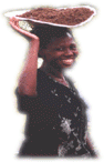 photo of African woman smiling and carrying a tray on her head