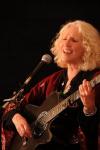 photo of Denise Jordan Finley singing & playing guitar in concert