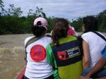 photo of three members of the IPO in a boat on a muddy river