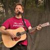 photo of David Rovics singing and playing guitar in concert