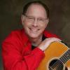 Red Grammer holding acoustic guitar and smiling at camera